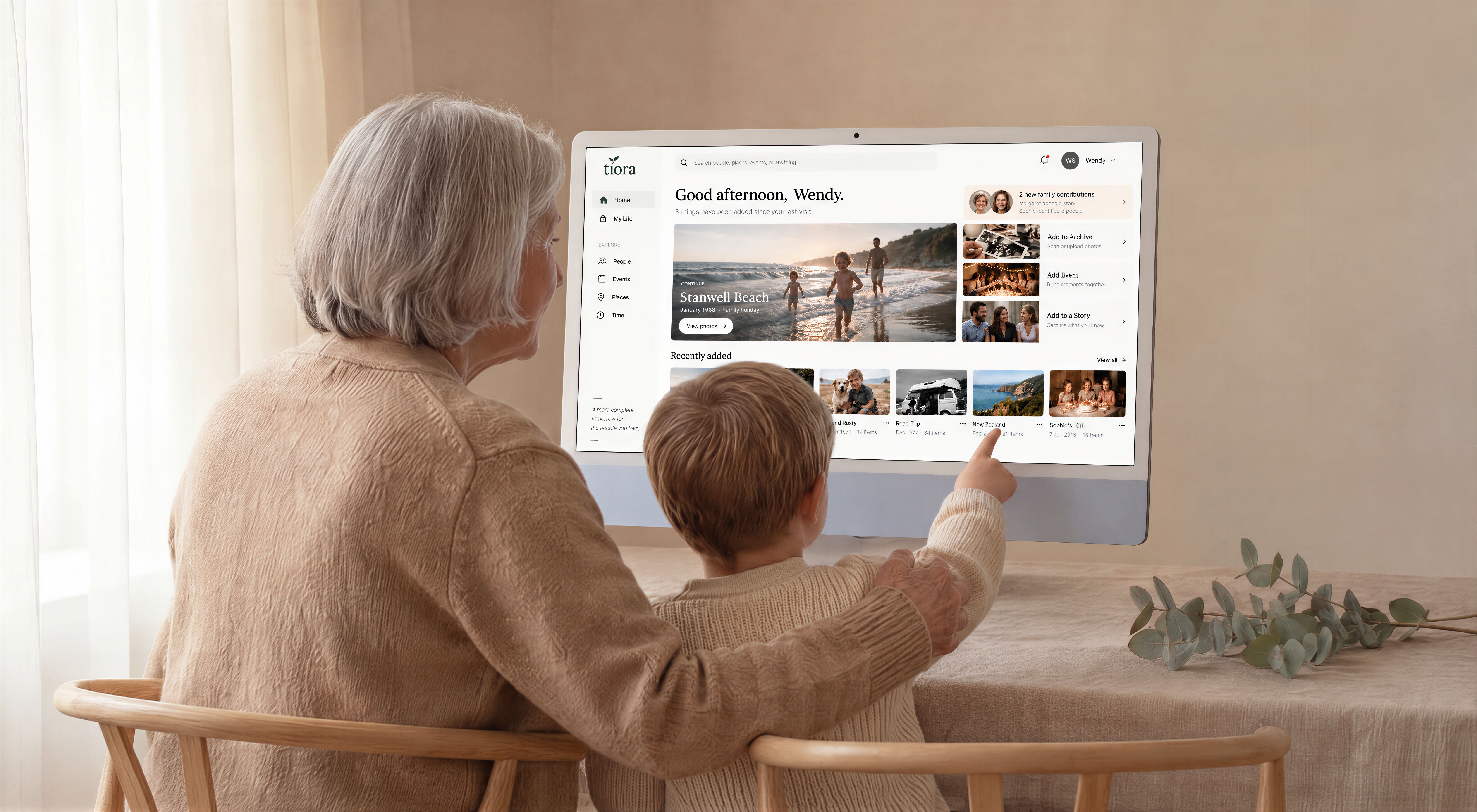 A grandparent and grandchild looking at family photos together on the Tiora Archive