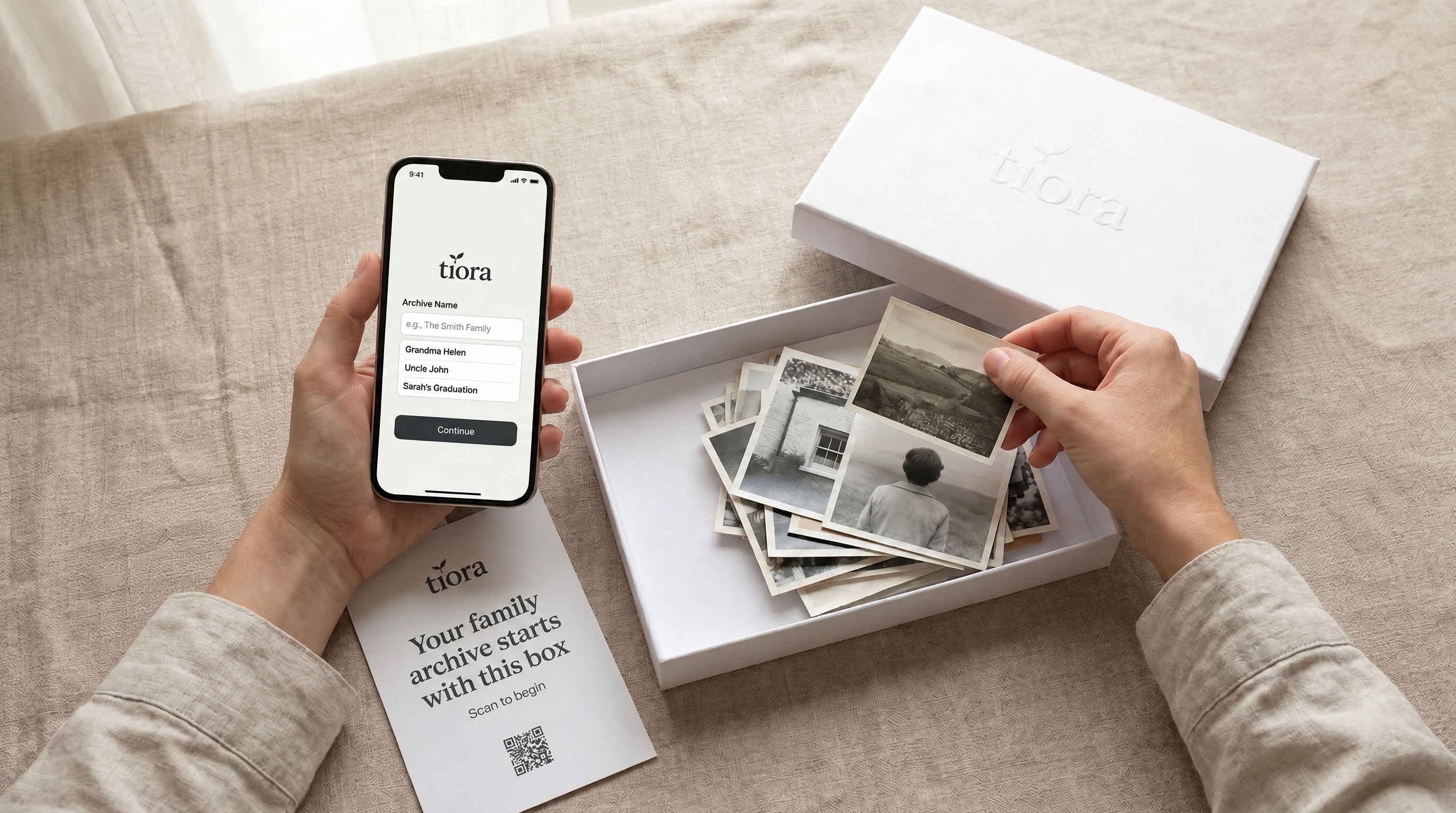 A phone starting a Tiora archive next to a box of family photographs