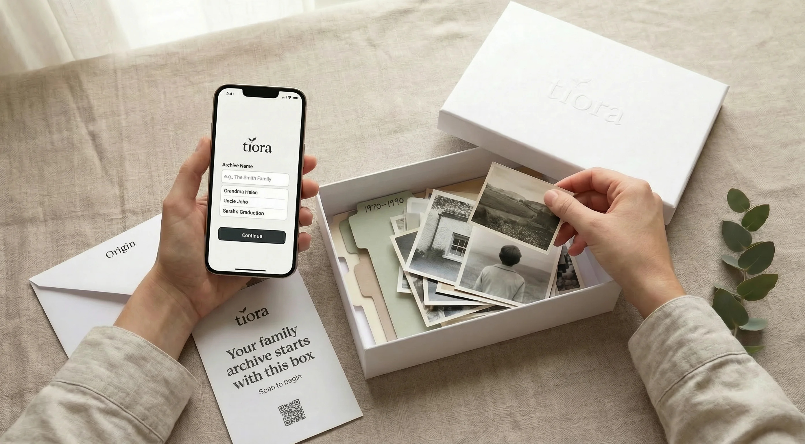 Hands opening a Tiora archive box beside vintage family photographs and the archive onboarding screen